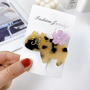 Detail view of cat-shaped acetate hair clip with floral accents and faux pearl details