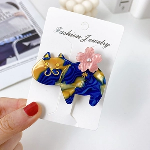 Detailed view of cat-shaped acetate hair clip with blue marble texture and pink flower