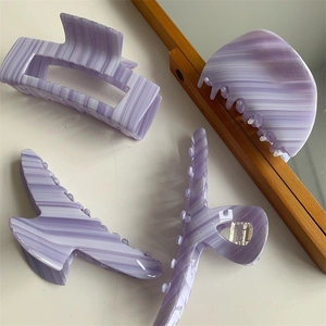 Macro detail of purple acetate hair claws with marble texture and striped patterns