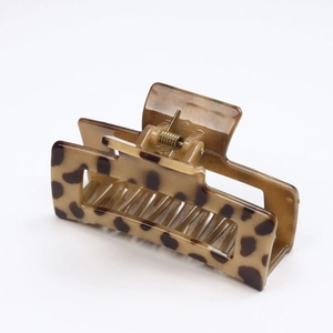 Detailed side view of a rectangular tortoise shell hair claw clip with golden metal spring