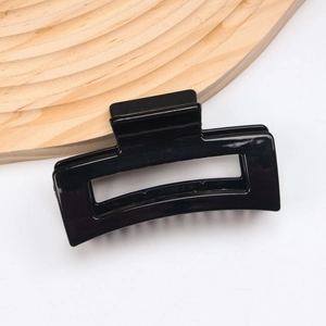 Detail of a minimalist black square hair claw clip with a glossy hollowed-out finish