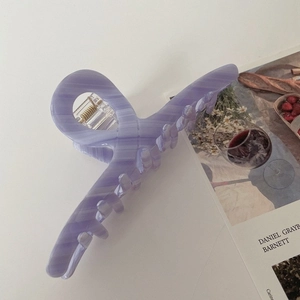 Detailed view of a purple marble acetate hair claw clip on an open magazine