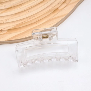 Detailed view of a transparent rectangular hair claw clip with golden metal spring