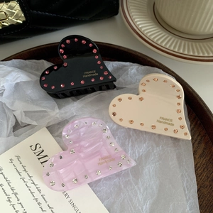 Tre fermagli a cuore in acetato con strass nei colori nero, crema e rosa marmorizzato