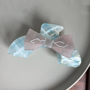 Macro shot of a blue and white checkered hair claw clip with a pink resin bow decoration