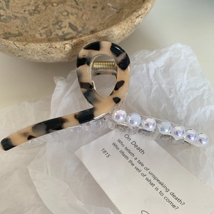 Détail d'une pince à cheveux écaille de tortue avec des perles irisées sur papier