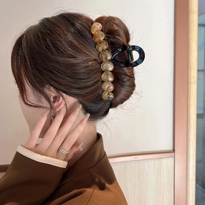 Detail view of a large black hair claw clip with amber resin hearts on a hair bun