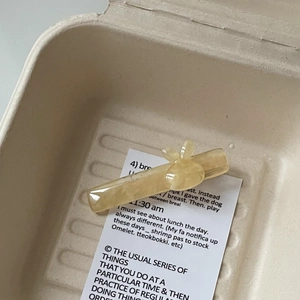 Vue détaillée d'une pince à cheveux en acétate ambré avec nœud transparent sur papier