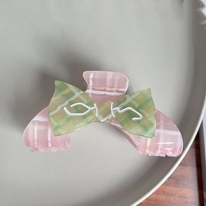 Detail of checkered pink hair claw clip with a contrasting green checkered ribbon bow