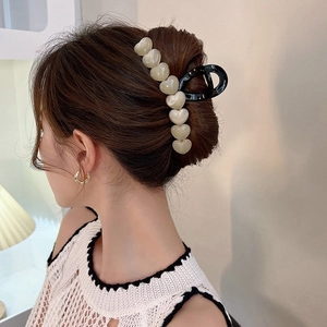 Pearlescent heart-shaped hair claw clip detail on elegant updo hairstyle for women