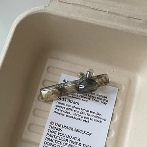 Détail d'une pince à cheveux lapin en acétate gris fumé sur une carte décorative anglaise