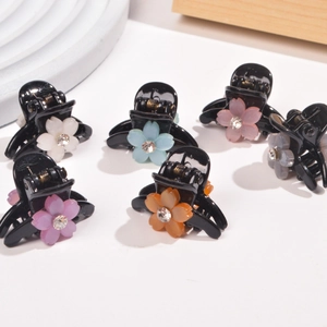 Close-up of small floral hair clips with resin petals and sparkling center rhinestones