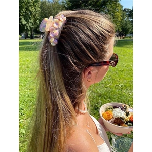 Haarklammer aus Acetat mit Blumenmuster und bunten Strasssteinen auf modischer Frisur