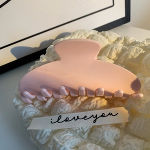 Gros plan d'une pince à cheveux rose mat sur tissu texturé avec ruban élégant