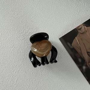 Detail view of a black resin hair claw clip with a brown marbled heart decoration