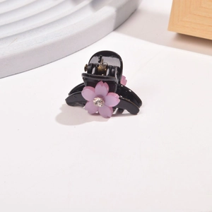 Detail of small black hair claw clip featuring a pink matte flower and sparkly rhinestone