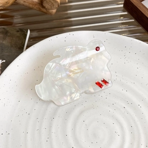 Détail macro d'une pince à cheveux lapin en acétate blanc avec strass rouges