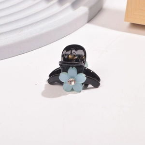 Close-up of a mini resin hair claw clip with a blue flower and sparkling crystal