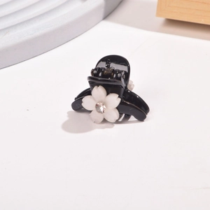 Detail of small black flower hair claw clip with crystal center and white petals