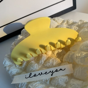 Vue détaillée d'une pince à cheveux en acétate jaune sur tissu blanc texturé