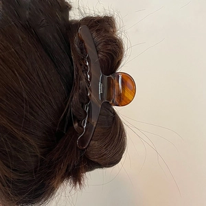 Detail view of large acetate claw clip with dark tortoise pattern on long hair