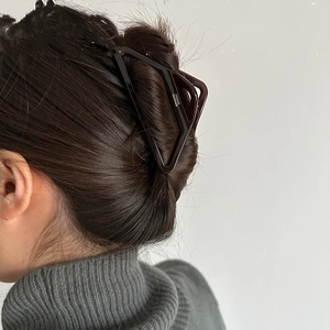 Detail view of large brown triangular acetate hair claw clip for elegant updo styling