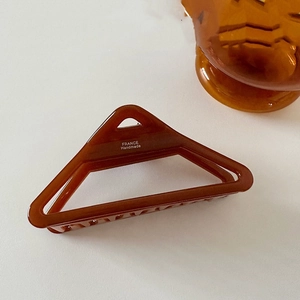 Detailed close-up of large amber acetate hair claw clip with France Handmade lettering