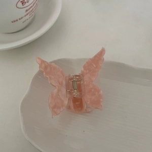 Detailed close-up of pink marble butterfly claw clip on a white decorative porcelain plate