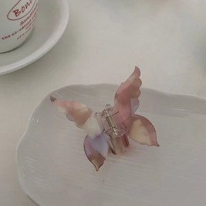 Detail view of pink butterfly hair claw clip with marble texture on ceramic tray