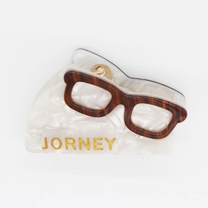 Detail of eyeglass-shaped acetate hair claw with JORNEY lettering and tortoise shell pattern