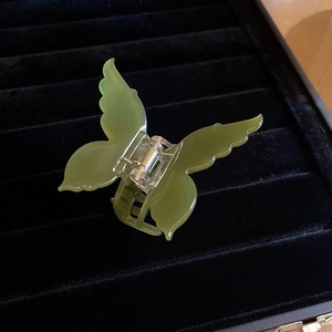 Translucent emerald green butterfly hair claw clip made of acetate on black velvet