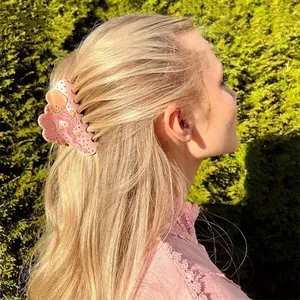 Rosafarbene Haarspange aus Acetat mit Goldglitzer, getragen von einem Modell im Freien
