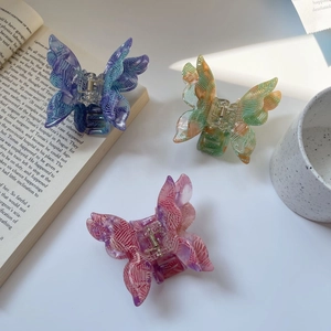 Three gradient butterfly hair claws with woven texture and acetate finish on a desk