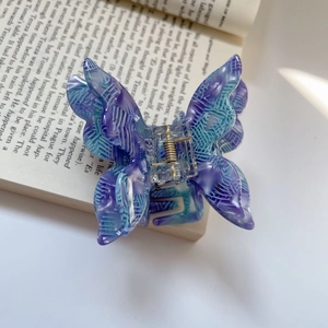 Detailed close-up of a marbled purple and blue butterfly hair claw clip on a vintage book