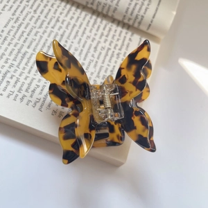 Detail of tortoiseshell butterfly hair claw clip with acetate finish on an open book