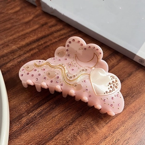 Detail der Haarklammer aus rosa Acetat mit Strasssteinen und Mondmuster in Makroansicht