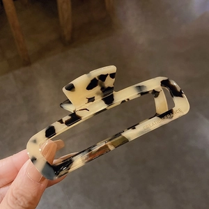 Gros plan sur la pince à cheveux en acétate marbré crème avec inscription dorée