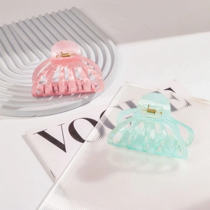 Detailed macro view of large pink and green acetate claw clips with gold metal springs