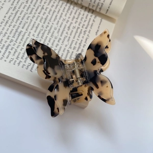 Detail view of acetate butterfly hair claw clip with tortoise shell pattern on book