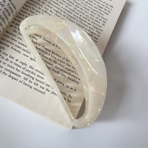 Macro view of cream white marble acetate hair claw with Creation France lettering