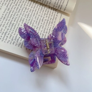 Detail shot of purple acetate butterfly hair claw with grid pattern on an open book