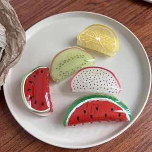 Acrylic fruit hair claws set featuring watermelon and kiwi designs on a ceramic plate