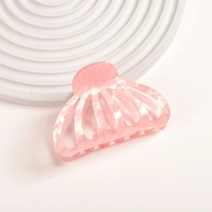 Detail view of pink acetate pumpkin hair claw clip on a white textured display base