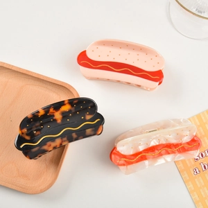 Detailed close-up of novelty hot dog shaped hair claws in acetate with mustard line detail