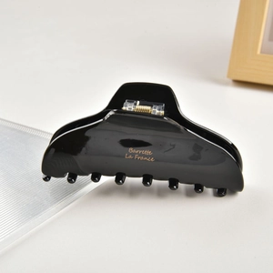 Detail of a large black acetate hair claw with gold spring and La France lettering