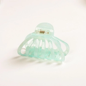 Detail view of large mint green acetate pumpkin hair claw clip with cutout geometric design