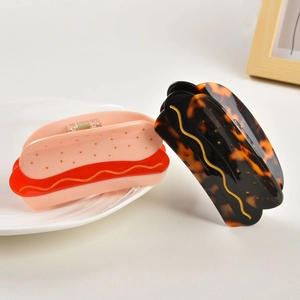 Detail showing two creative hot dog shaped hair claw clips with unique acetate patterns