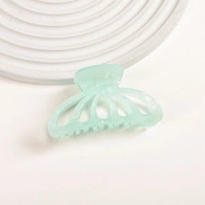 Close-up of light mint green acetate pumpkin hair claw clip on a white display tray