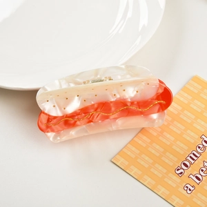 Detail shot of the acetate hot dog hair claw with colorful resin layers and gold wavy lines