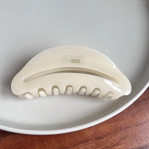 Detailed macro view of cream cellulose acetate hair claw clip with France handmade logo